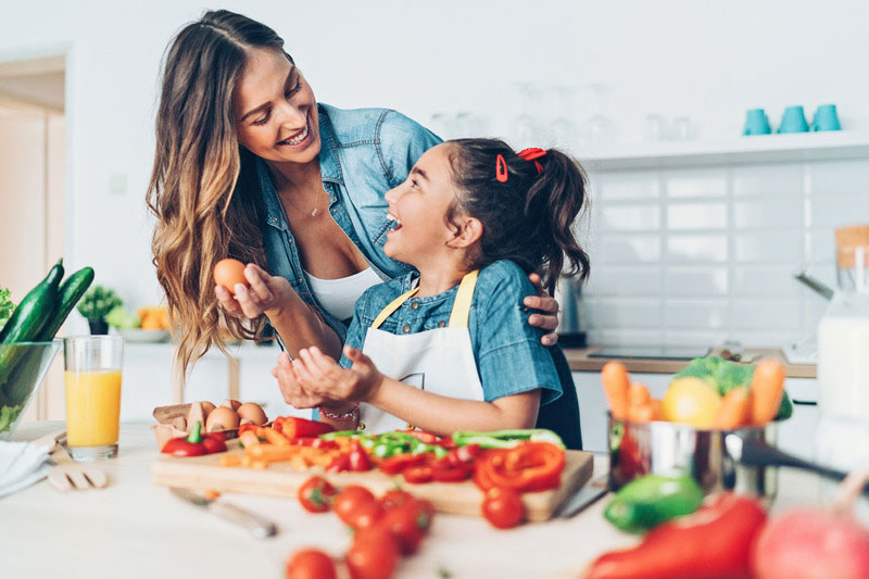 caregiver making a meal with child in the kitchen