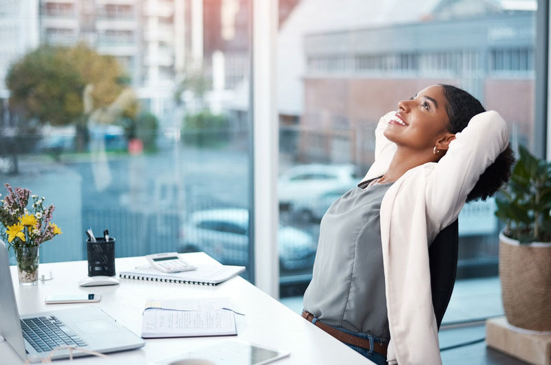 woman sitting at her desk smiling and relaxed