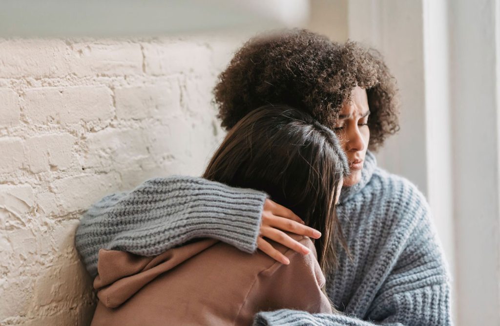 two women hugging each other for comfort