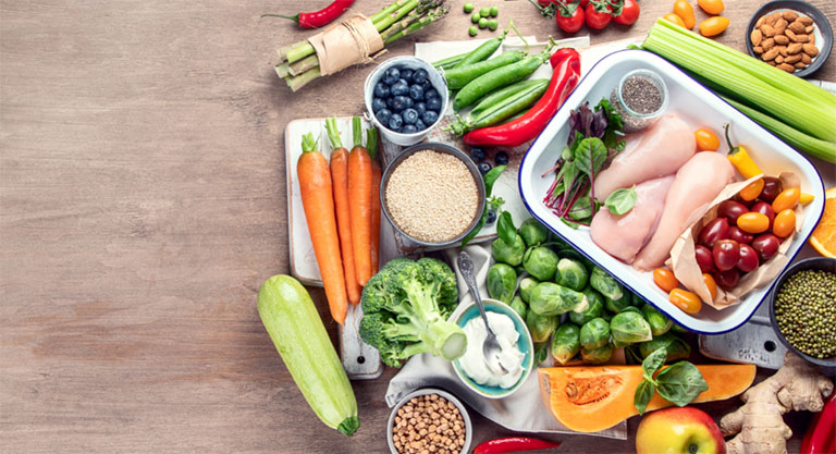 A bunch of fruits and vegetables sitting on a wooden table.