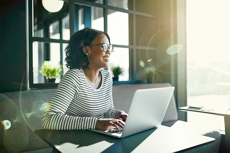 smiling business woman sitting at desk working on laptop