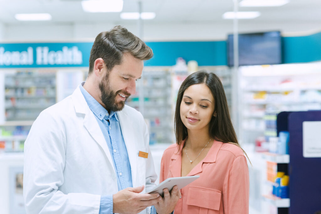 Shot of a pharmacist using a digital tablet while assisting a customer
