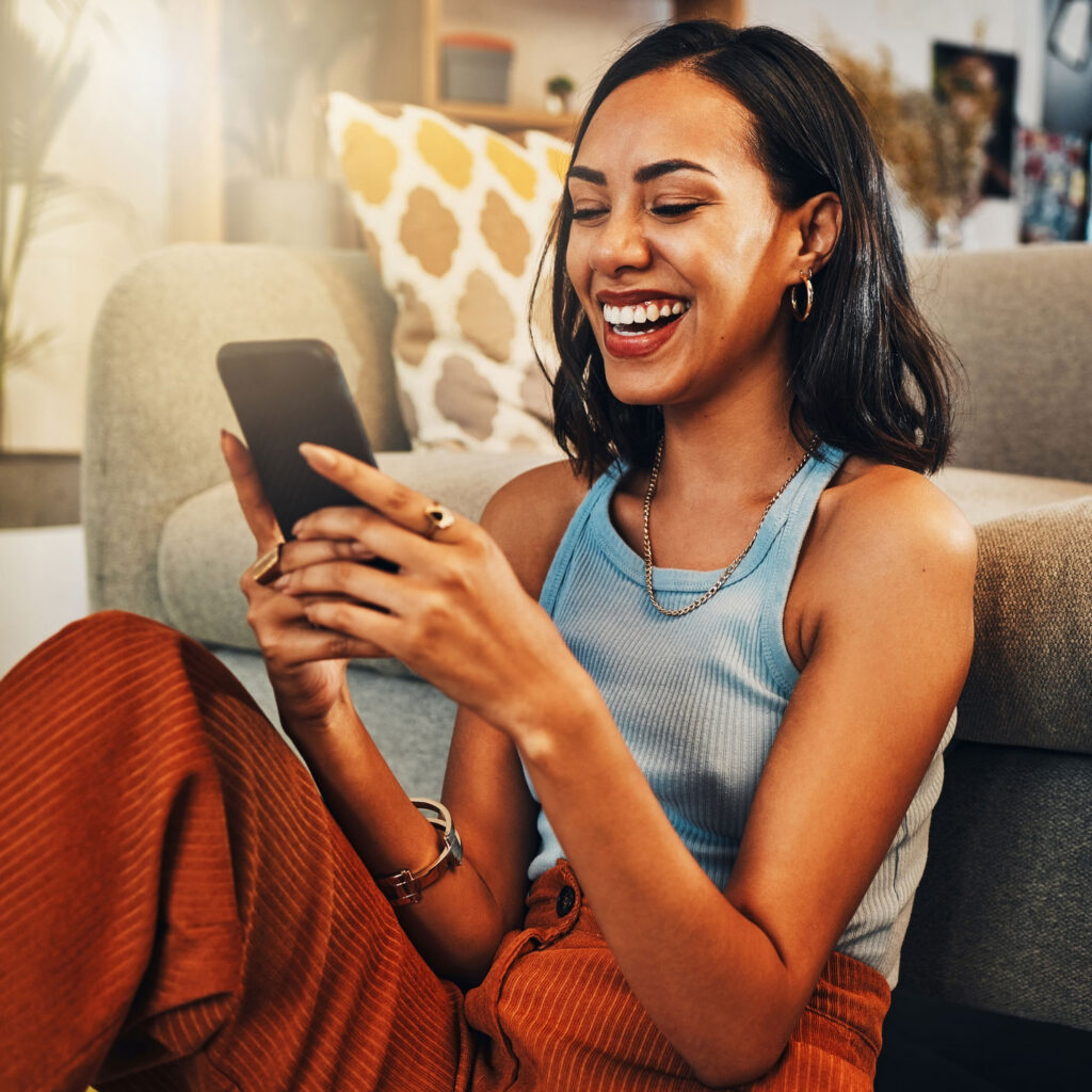 woman sitting on couch looking and interacting with mobile phone